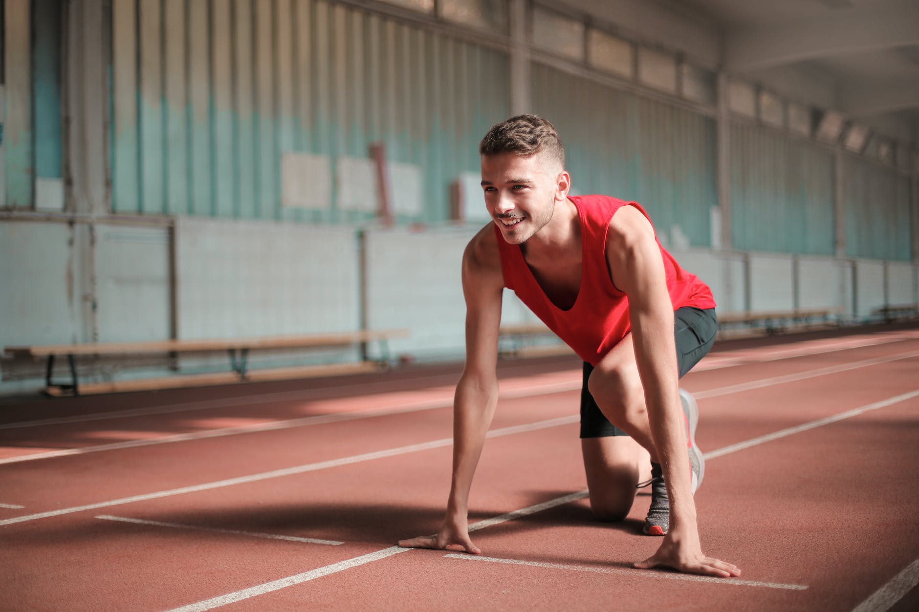 photo of smiling man in active wear on his marks on running track
