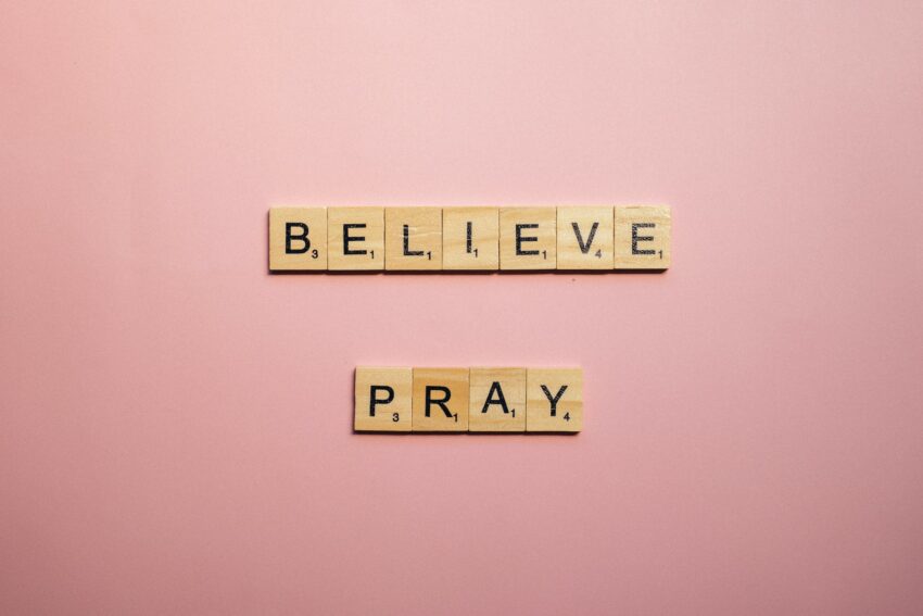a believe and pray words of encouragement on pink surface