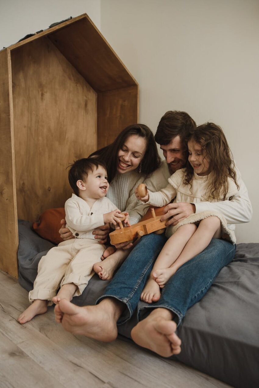 family sitting on bed playing with wooden toy