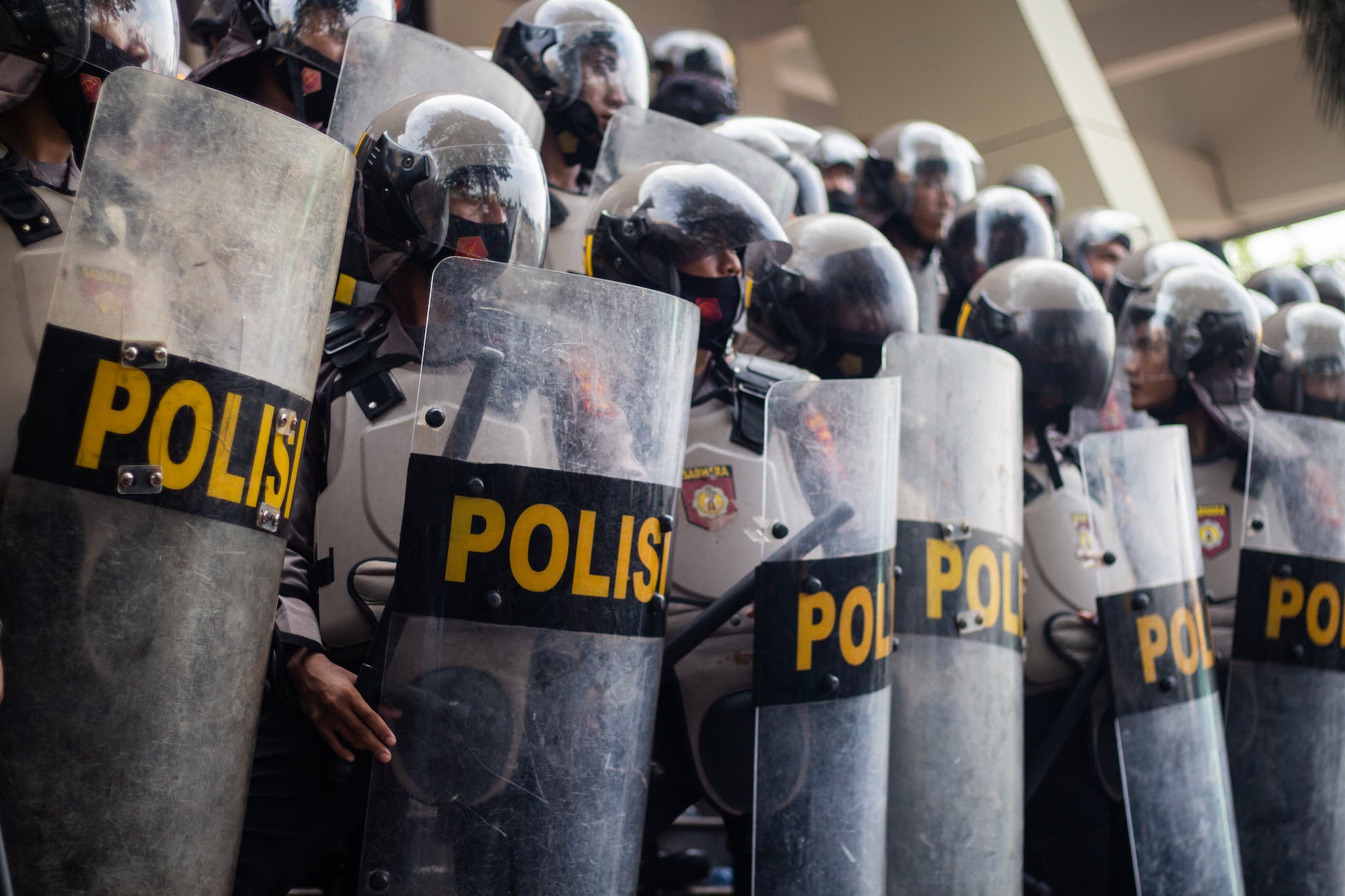policemen wearing black helmets standing on the street holding police shields
