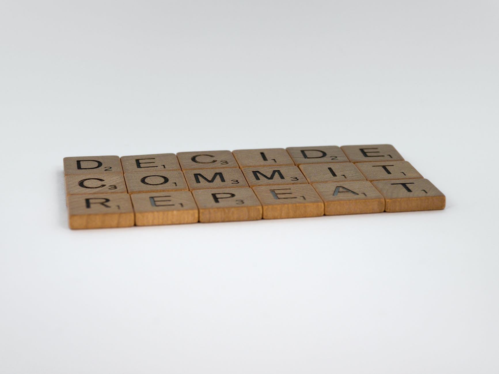 decide commit repeat a scrabble tiles quote on a white background