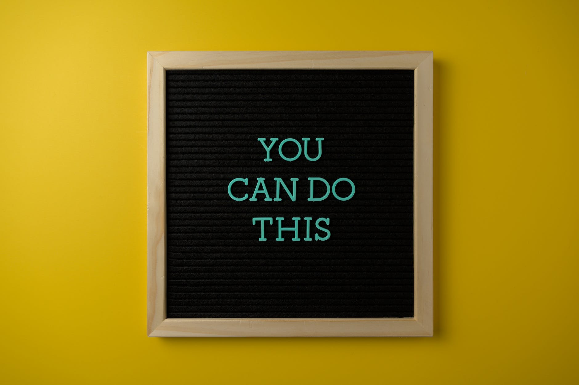 framed board with a motivational slogan on a yellow wall